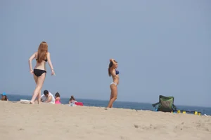 Redhead and brunette friends looking sexy in bikinis on the beach