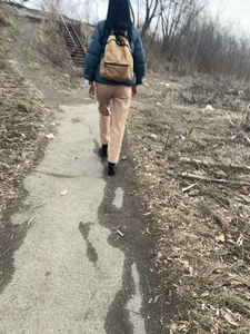Candid girl wearing pants and a backpack walking down a suburban road