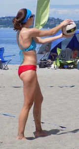 Skinny mature lady in red bikini bottom on the beach playing volleyball
