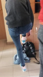 Candid Teen Girl in Skinny Jeans Standing on One Leg While Tying Her Shoelaces