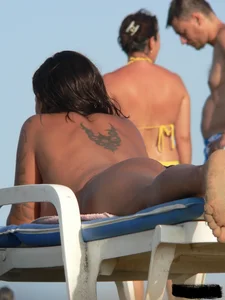 Topless tattooed lady on the beach with fake big tits
