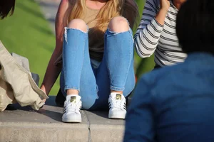 Girl in Blue Torn Jeans Sitting in the Park Creepshots