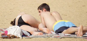 Sexy girl on the beach laying out and bending over in her bikini