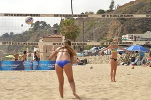 Sexy beach volleyball girl in sport bra top with pokies and blue bikini bottom
