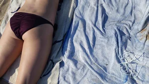Hot girl laying on the beach in her purple bikini