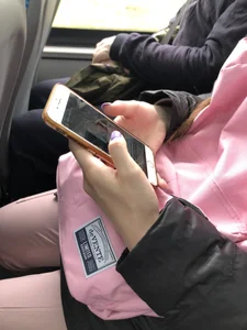 Cute teen girl's manicured hands holding a phone in a public bus creepshots