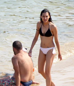 Skinny brunette girl on the beach in black and white bikini