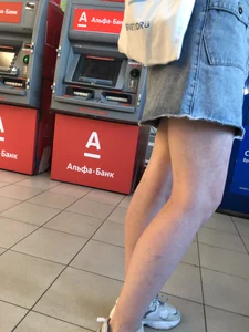 Young Candid Girl With Slim Pale Legs In a Denim Skirt Waiting in the Queue
