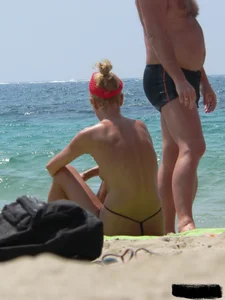 Topless skinny blonde lady in a g-string bikini at the beach