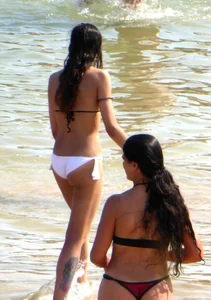 Skinny brunette girl on the beach in black and white bikini