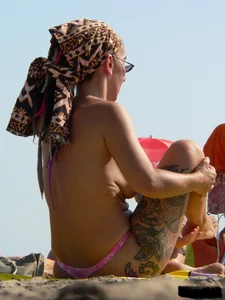 Topless tattooed lady at the beach with a nice ass in pink thong bikini