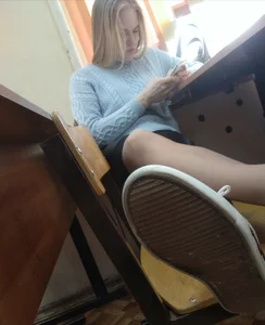 Cute Girl Sitting With Her Skinny Legs in Pantyhose Crossed