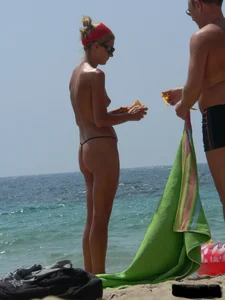 Topless skinny blonde lady in a g-string bikini at the beach