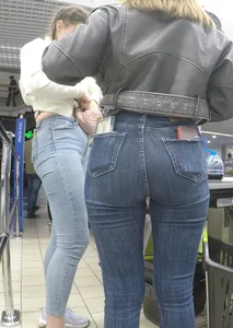 Two hot milfs in tight blue jeans standing at the cash register at the supermarket, awesome big butts