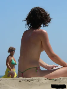 Topless beach milf looking sexy in a tiny g-string bikini