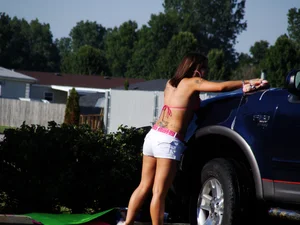 Group of cute girls at a car wash in bikinis and shorts