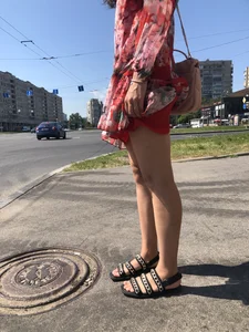 Hot street candid girl wearing a short dress and sandals standing on the crosswalk, wind is playing with her hair