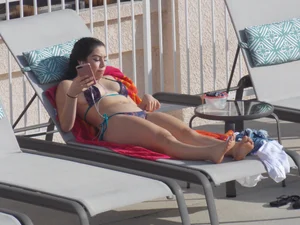 Sexy ass brunette sunbathing by the pool in thong bikini