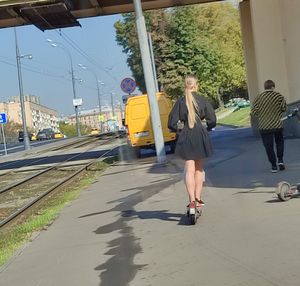 Cute candid blonde wearing a summer dress riding an electric scooter, slim hot legs