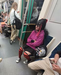 A candid gothic girl wearing striped stockings and a skirt sitting in a subway train creepshot, nice legs